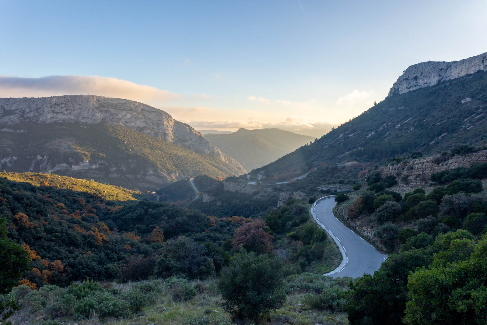 Vue plongeante sur la route sinueuse du col de l'espigoulier dans un paysage de Guarrigues dans une lumière cuivrée